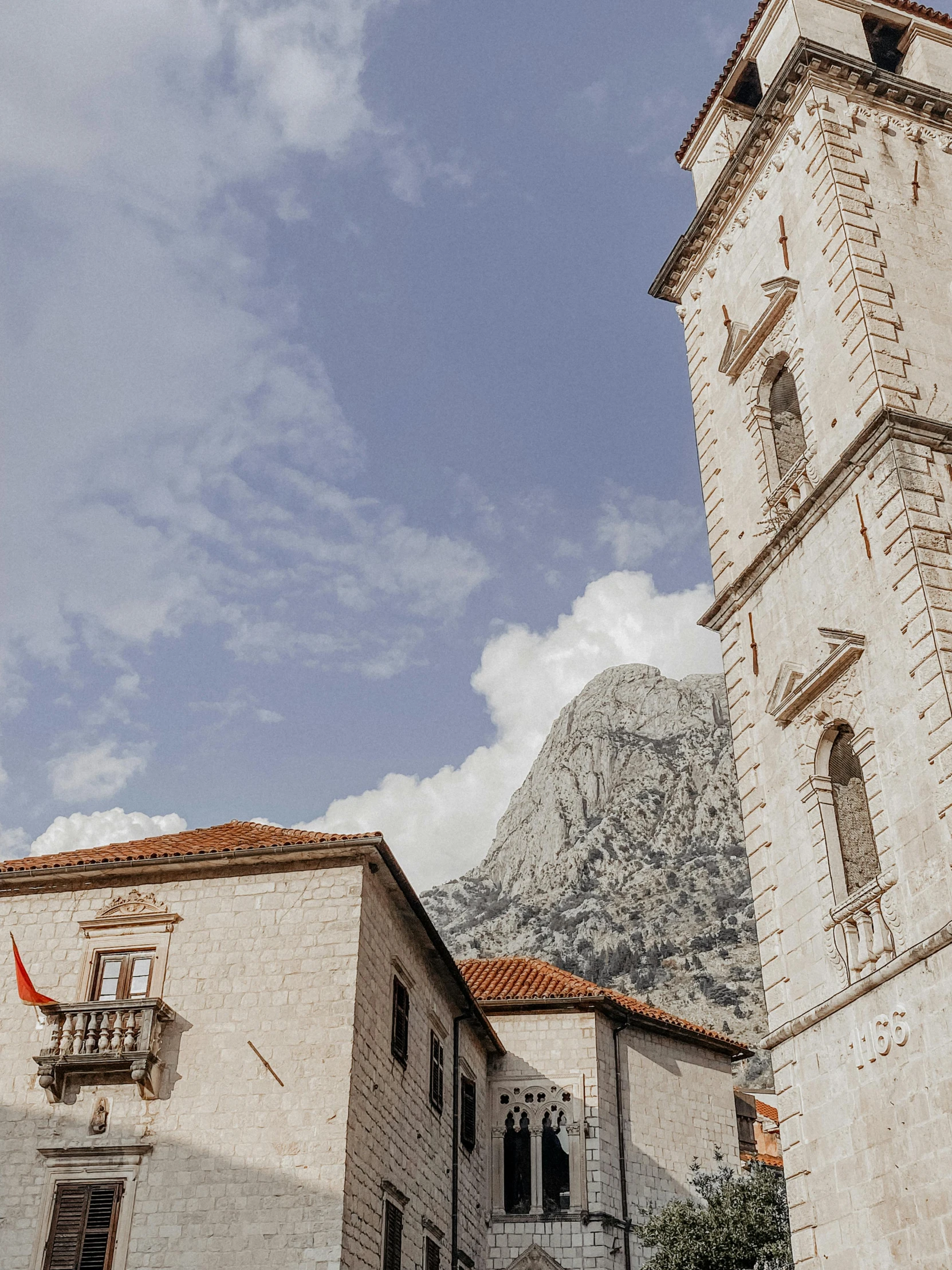 a tall clock tower sitting in the middle of a town, by Emma Andijewska, pexels contest winner, romanesque, boka, two mountains in background, high details photo, square