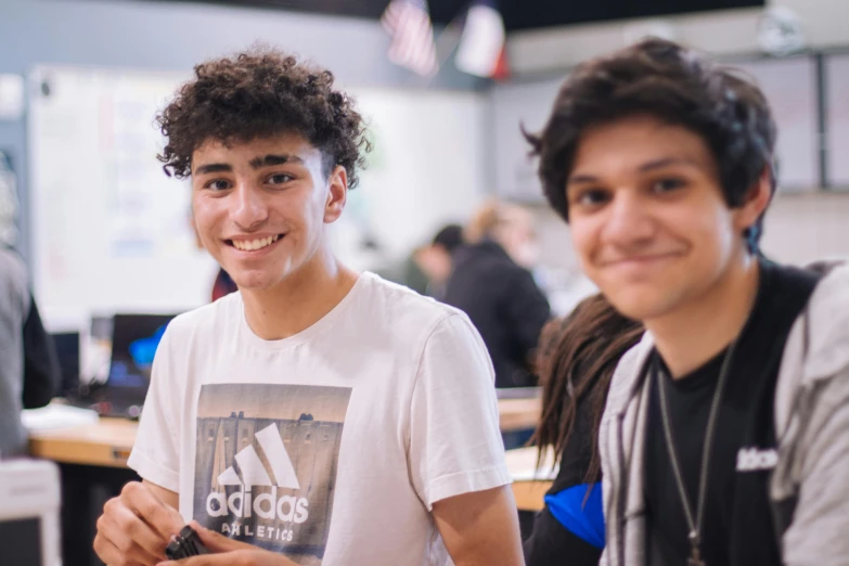 a couple of young men sitting next to each other, a colorized photo, pexels contest winner, ashcan school, smiling and looking directly, assyrian, focus in the foreground, avatar image