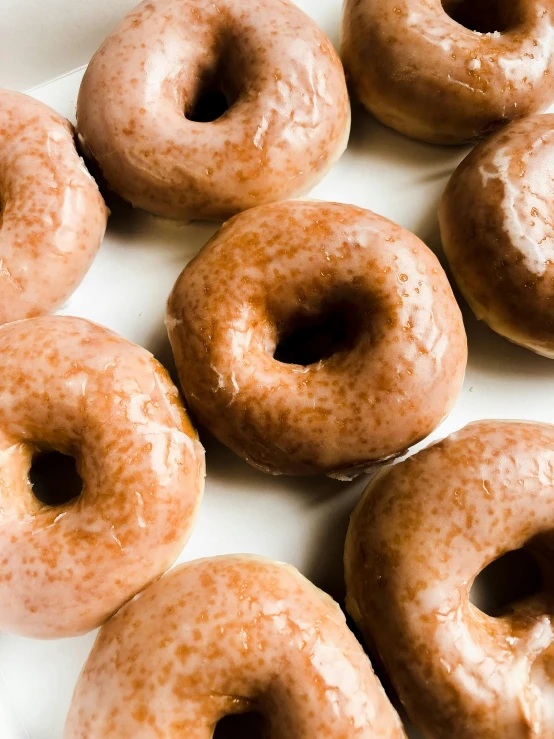 a white plate topped with lots of glazed donuts, a portrait, by Robbie Trevino, unsplash, cinnamon skin color, chocolate frosting, close up to a skinny, ignant