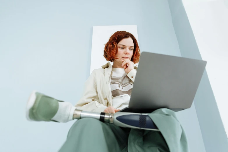 a woman sitting on a chair using a laptop, a hyperrealistic painting, trending on pexels, prostheses, hr ginger, holding lightsaber, human staring blankly ahead