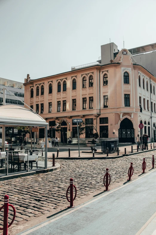 a group of people walking down a street next to tall buildings, byzantine, restaurant in background, cobblestones, high quality image