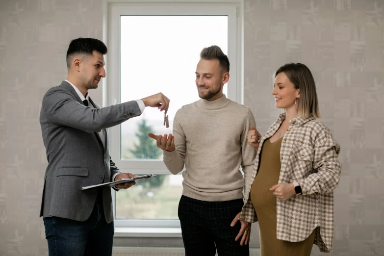 a couple of people standing in front of a window, selling insurance, pregnant, developers, brown