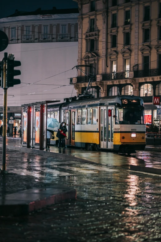 a street filled with lots of traffic next to tall buildings, by Tobias Stimmer, unsplash contest winner, viennese actionism, bus stop on a rainy day, trams ) ) ), busy wet street at night, square