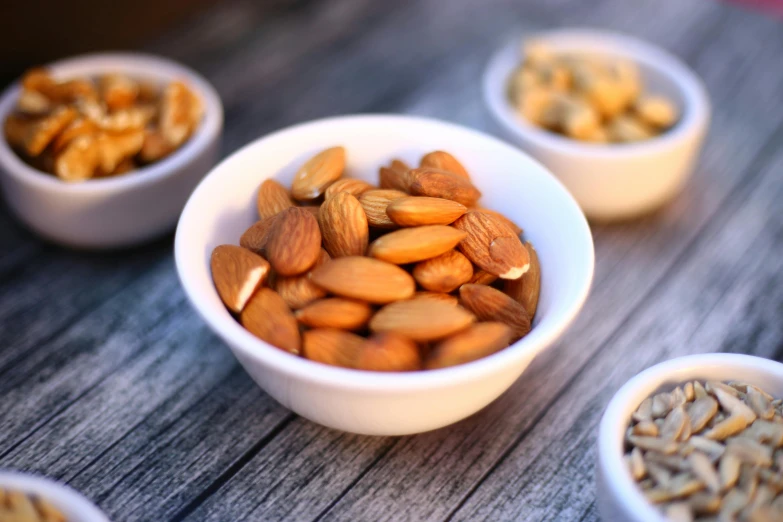 a white bowl filled with nuts on top of a wooden table, pexels, 🦩🪐🐞👩🏻🦳, miniature product photo, stacked image, thumbnail