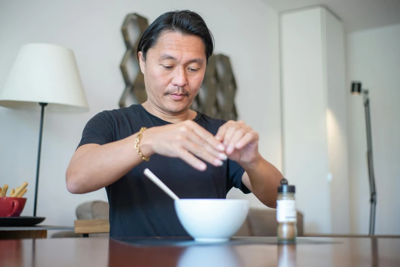 a man in a black shirt putting a spoon into a bowl