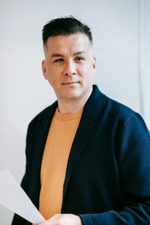 a man with black hair holding a piece of paper