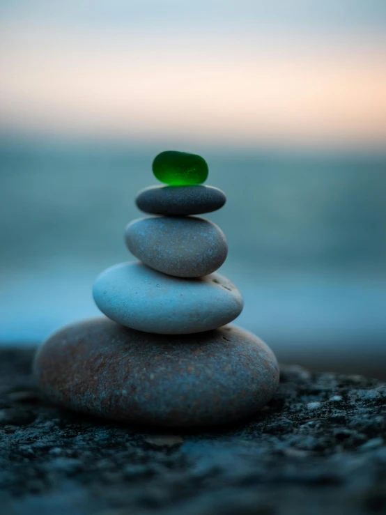 a stack of rocks sitting on top of a beach, profile image, glowing green rocks, centred, small stature