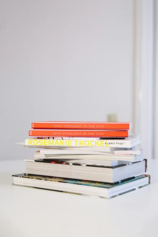 a stack of books sitting on top of a table, white and orange, on a white table, dwell, for displaying recipes