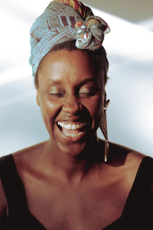 a smiling woman with a turban on her head, an album cover, inspired by Makoto Aida, trending on unsplash, diffused natural skin glow, grace jones, close-up portrait film still, in 2 0 0 2