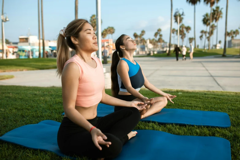 two women in yoga attire doing different poses on a blue yoga mat