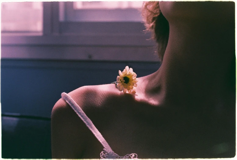 a sunflower stuck to the side of a womans neck