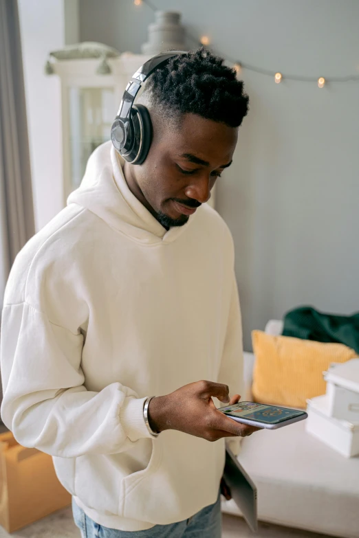 a man wearing headphones looking at a cell phone, trending on pexels, wearing a white sweater, jaylen brown, avatar image, uploaded