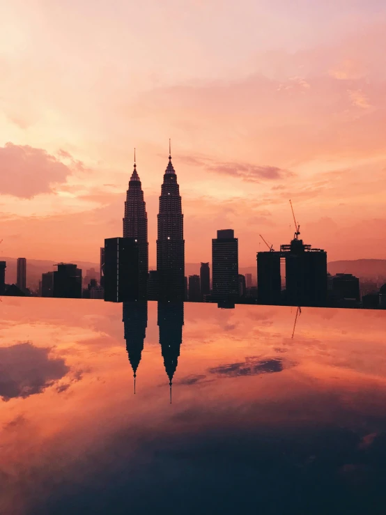 the reflection of two buildings in the water, by Bernardino Mei, pexels contest winner, hurufiyya, skyline view from a rooftop, orange / pink sky, malaysian, album cover