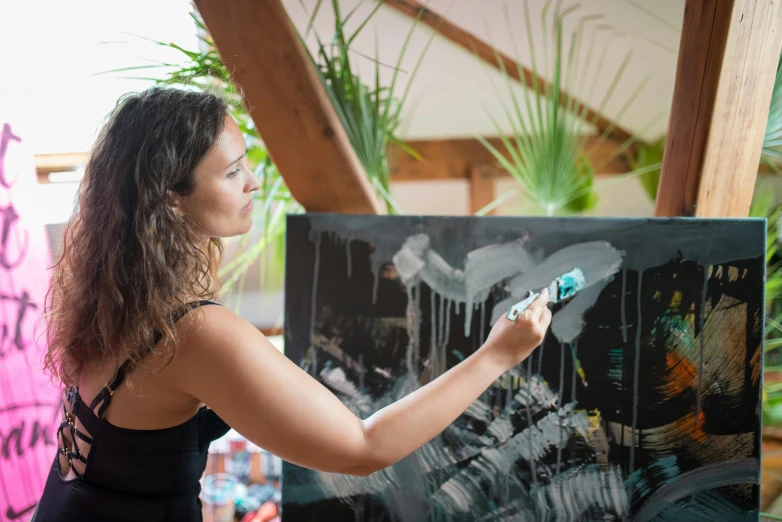 a woman that is standing in front of a painting, a hyperrealistic painting, by Amédée Ozenfant, pexels contest winner, action painting, holding a paintbrush, abstract painting in black, lush vista, detailed acrylic