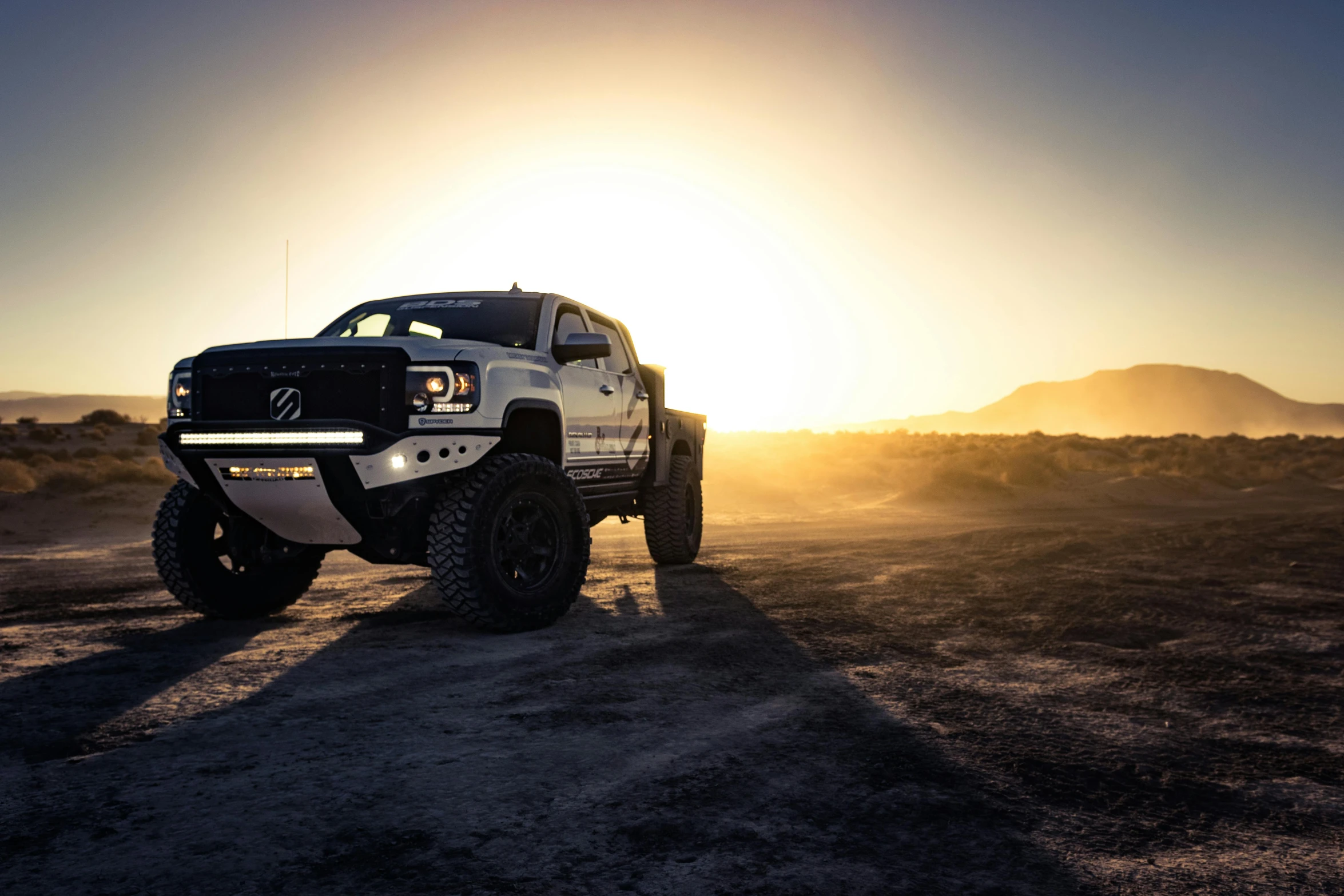 the white truck is on a dirt road in the desert