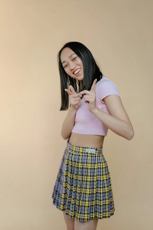 a woman in a skirt making a peace sign, inspired by helen huang, trending on pexels, y 2 k cutecore clowncore, straight hairstyle, product introduction photo