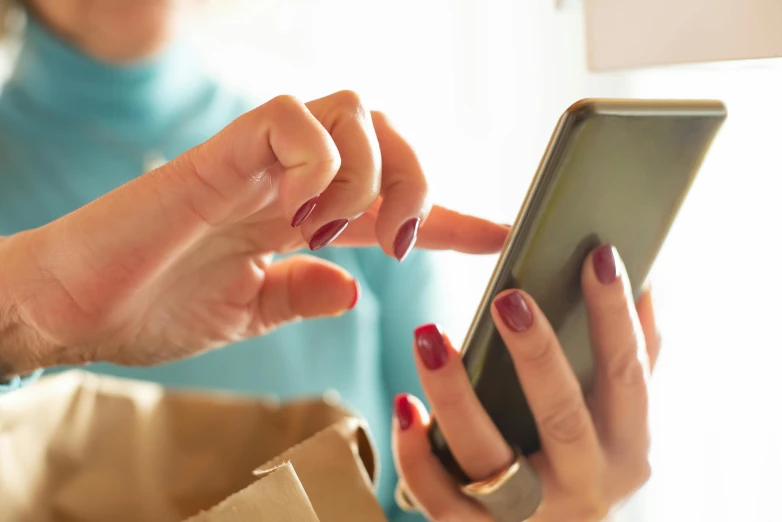 a close up of a person using a cell phone, at checkout, painted nails, cardboard, avatar image