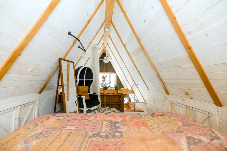 attic bedroom with high ceiling and bed has wooden furniture