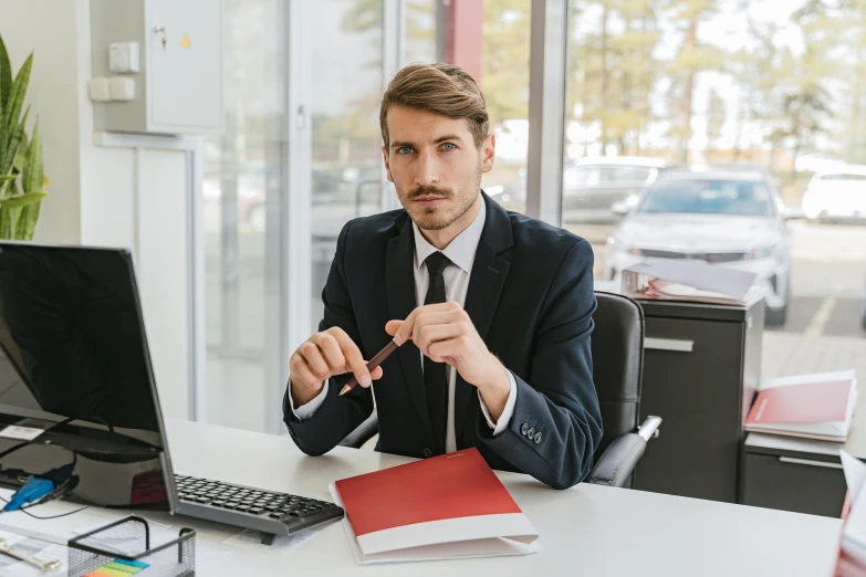 a man sitting at a desk in front of a computer, holding a whip, wearing a suit and tie, liam brazier, selling insurance