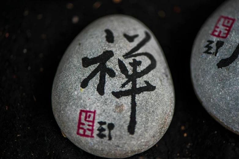 two asian writing painted on large rocks sit next to each other