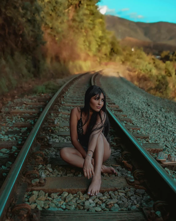 a woman in bathing suit sitting on train tracks
