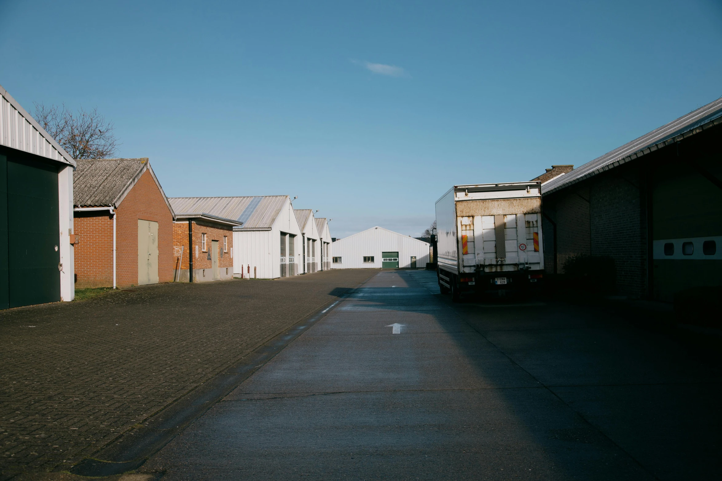 a truck parked on the side of a road next to a building, by Daniel Seghers, unsplash, warehouses, of augean stables, endless hallways, john pawson