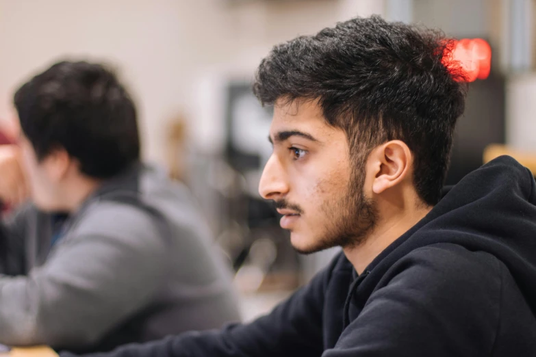 a man sitting in front of a laptop computer, a picture, trending on pexels, academic art, looking from side, riyahd cassiem, boy with neutral face, in focus face with fine details