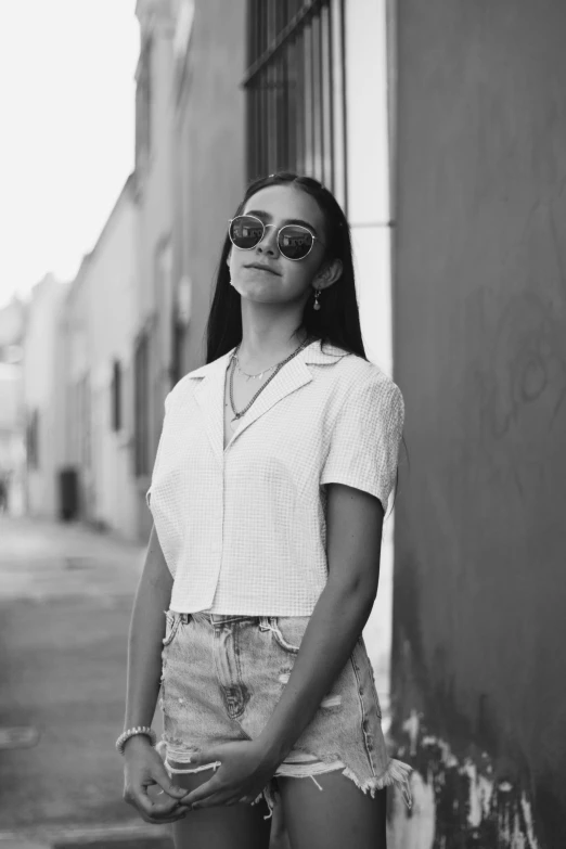 a black and white photo of a woman leaning against a wall, inspired by Amelia Peláez, pexels contest winner, wearing cool sunglasses, wearing a light shirt, wearing crop top, a young asian woman