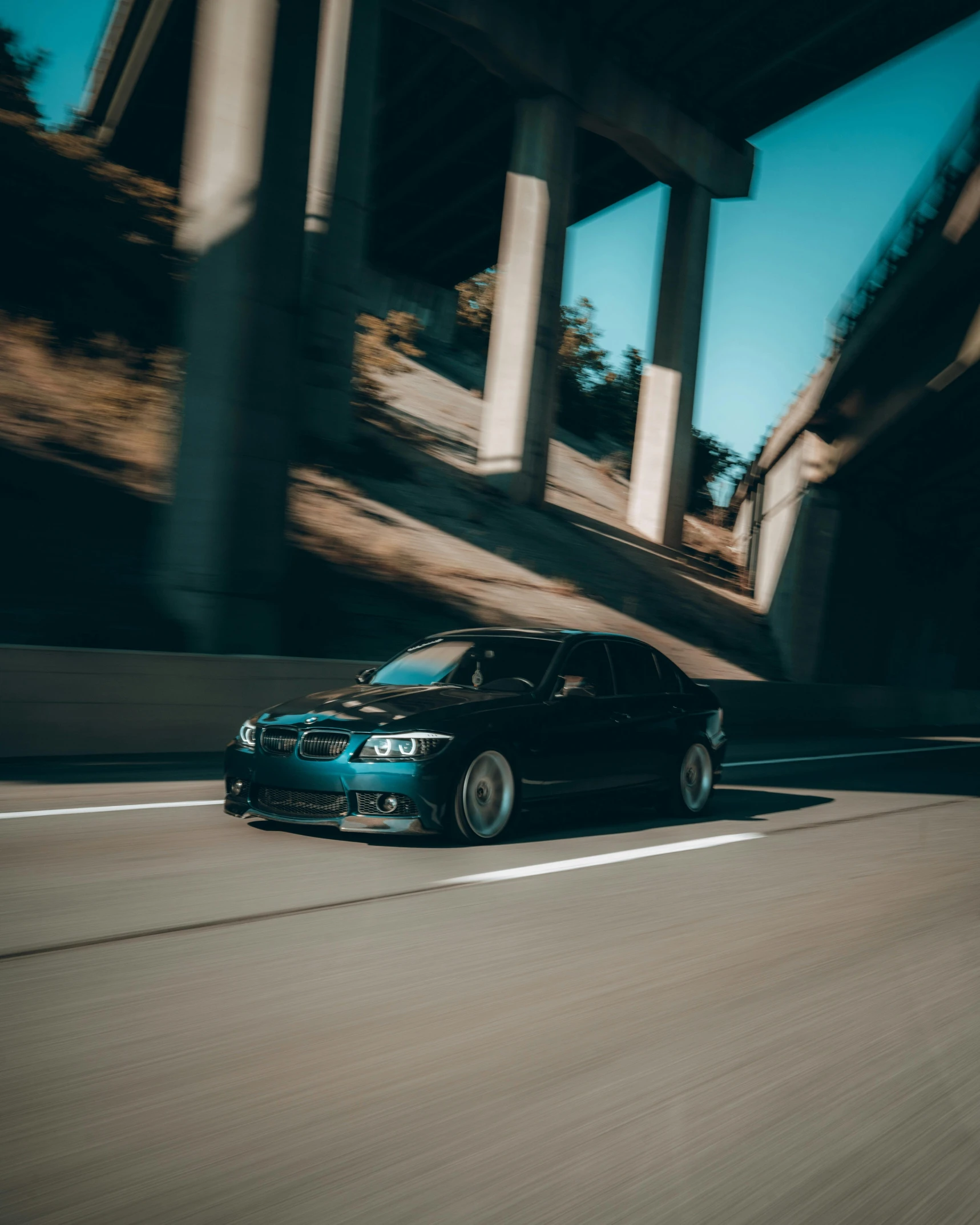 a black car on the street passing under a bridge