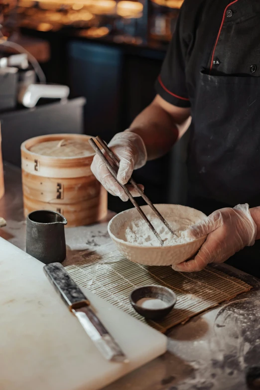 a person in a kitchen preparing food with chopsticks, covered in white flour, gourmet and crafts, simon lee, order