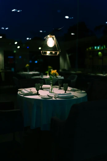 a dimly lit dining room with tables and chairs, by Jesper Knudsen, soft outdoor light, chef table, looking sad, lights with bloom