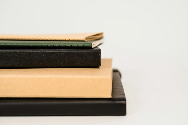 a stack of three books sitting on top of each other, an album cover, unsplash, private press, black and brown, holding notebook, looking from side, portrait close - up