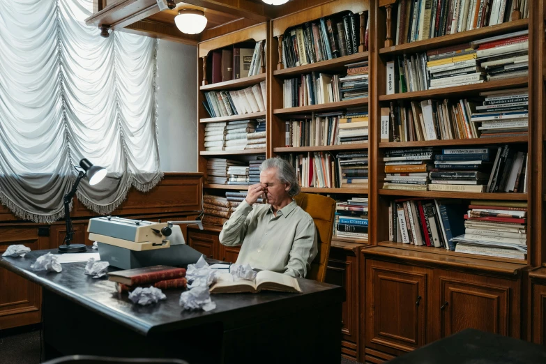 a man sitting at a desk with a typewriter, a portrait, by Elsa Bleda, pexels contest winner, a silver haired mad, bookshelves on sides, azamat khairov, full body image