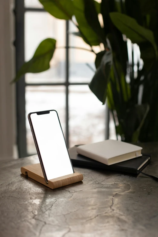 a cell phone sitting on top of a wooden stand, unsplash, renaissance, oled lights in corners, square, dwell, eco