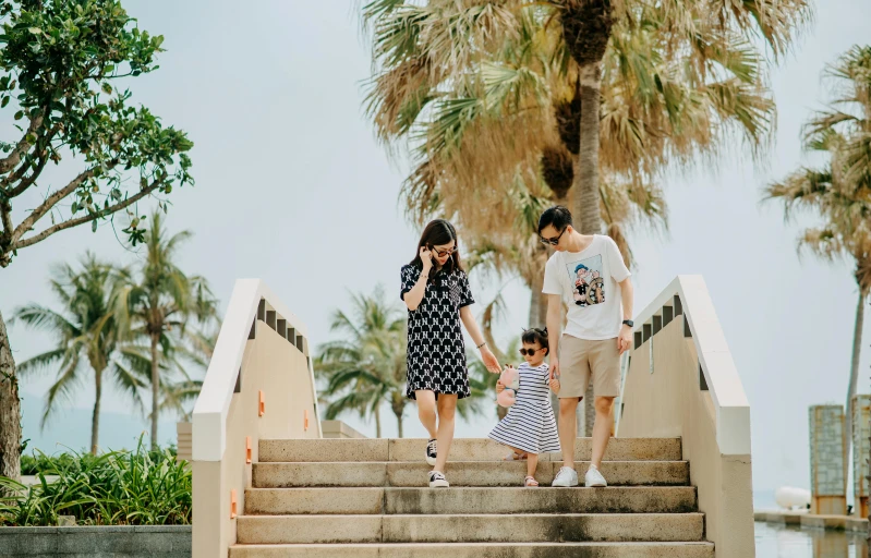 a group of people walking up a flight of stairs, pexels contest winner, portrait of family of three, palm trees in the background, cute:2, fashion