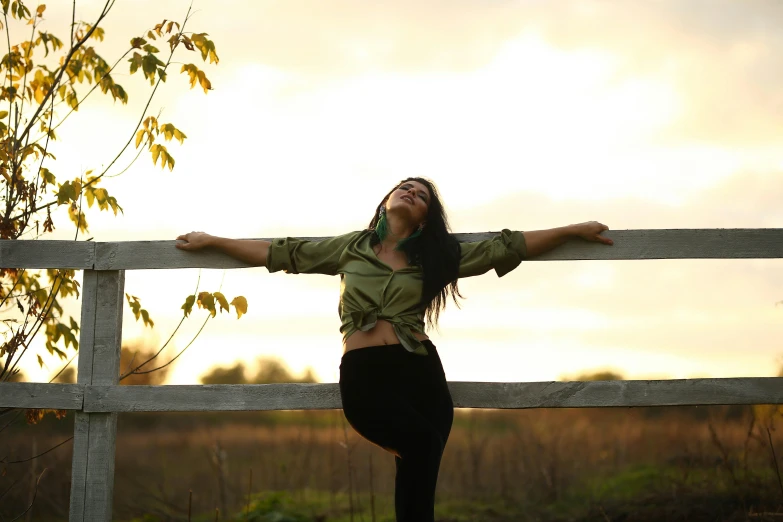 a woman leaning on a fence next to a tree