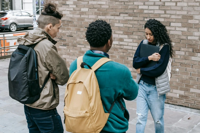 several people standing in front of a brick wall talking