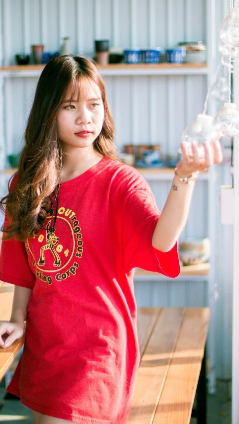 a woman in a red shirt standing in front of a refrigerator, inspired by Gong Kai, instagram, wearing a marijuana t - shirt, mid shot photo, official product image, asian