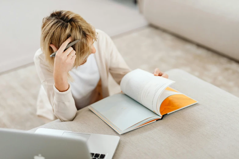 a woman sitting at a table with a laptop and cell phone, trending on pexels, academic art, an open book, flat minimalistic, thumbnail, working in a call center