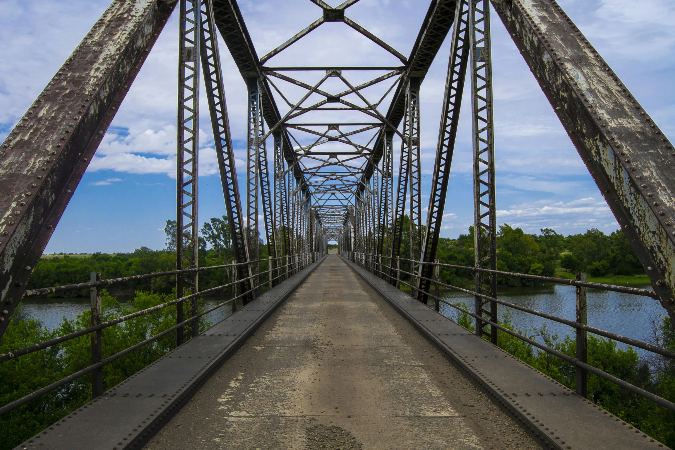 a long metal bridge over a body of water, unsplash contest winner, southern gothic, on a bright day, thomas river, paul davey