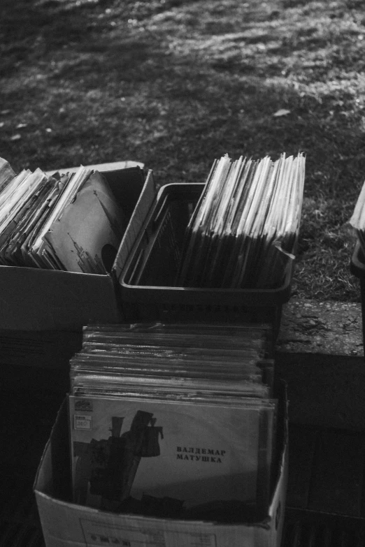 a black and white photo of a pile of records, unsplash, in the yard, cigarrette boxes at the table, half image, [ metal ]