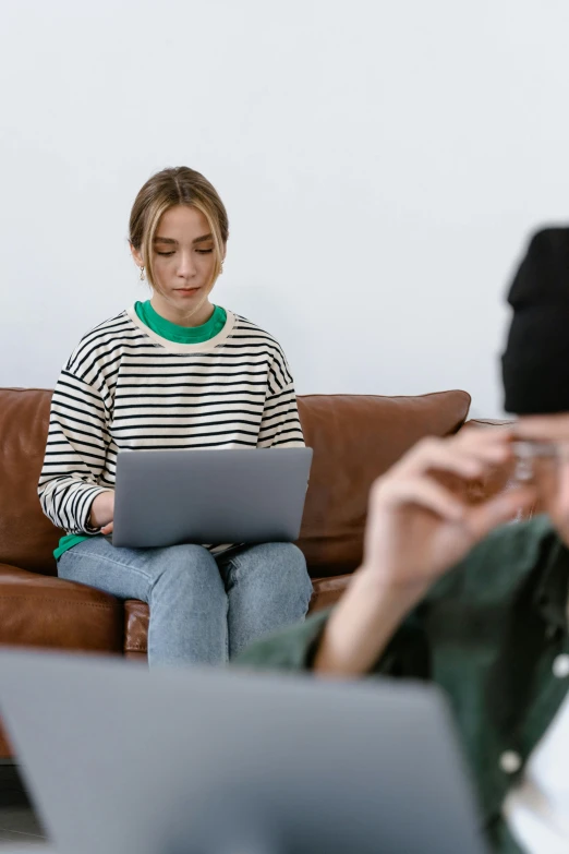 a woman sitting on a couch using a laptop, by Adam Marczyński, trending on pexels, medium shot of two characters, stalking, casually dressed, professional photo