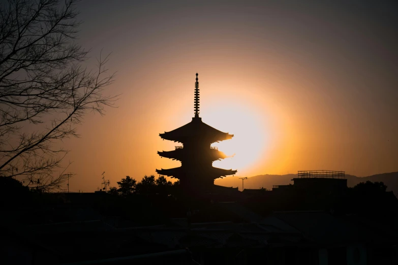 a pagoda is silhouetted against the setting sun, inspired by Itō Jakuchū, pexels contest winner, ancient silver tower of the moon, portrait photo, brown, shot on sony a 7