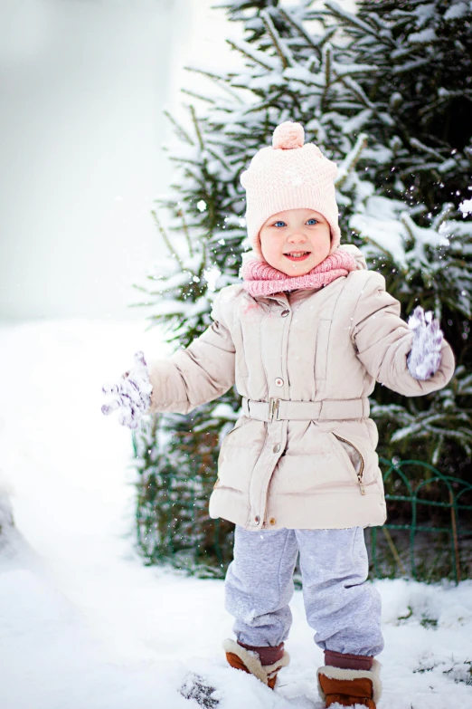 a young child walking in the snow with her hands up