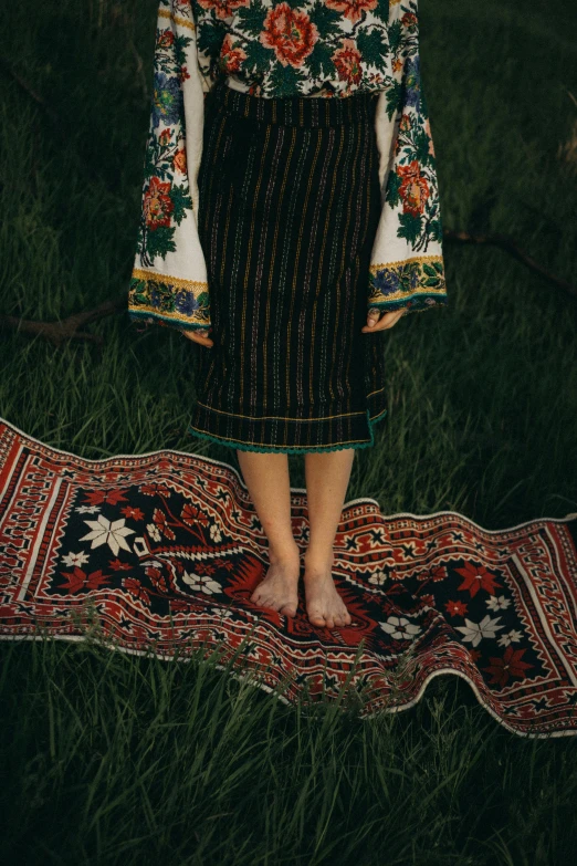 the legs of a young woman standing on a rug in a field