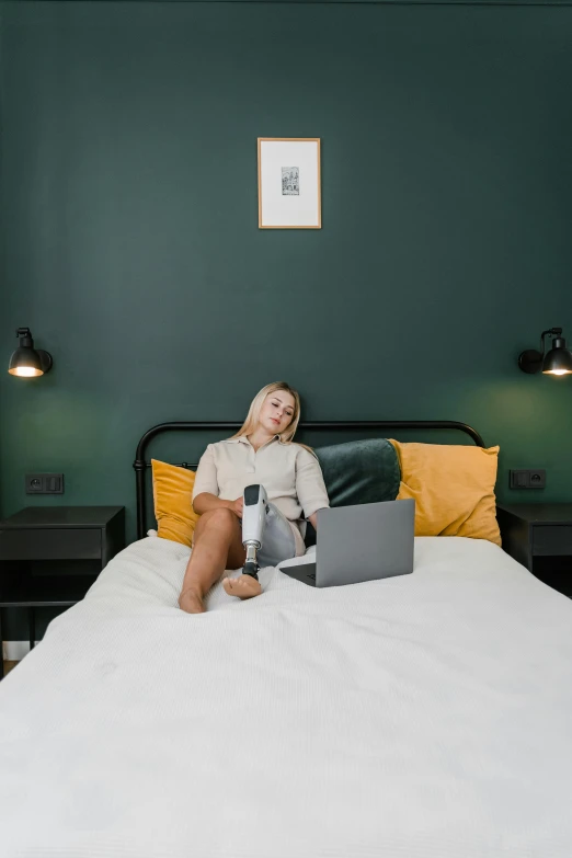 a woman sitting on a bed and typing on her laptop