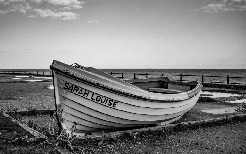 a boat sitting on top of a beach next to the ocean, a black and white photo, inspired by Samuel Prout, pixabay, square, yorkshire, 💋 💄 👠 👗, sarah cliff