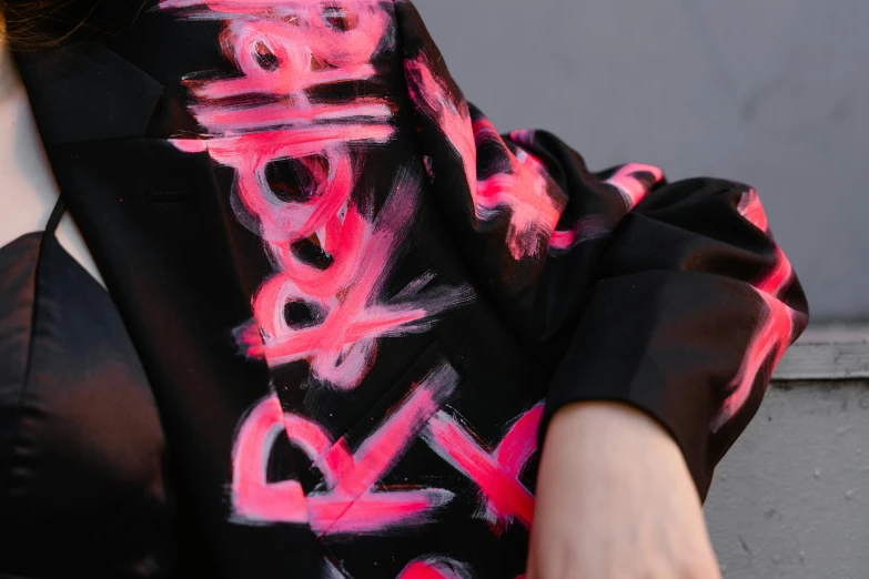 a woman wearing a black shirt with pink graffiti on it, trending on pexels, silk robes, detail shot, ((pink)), signatures