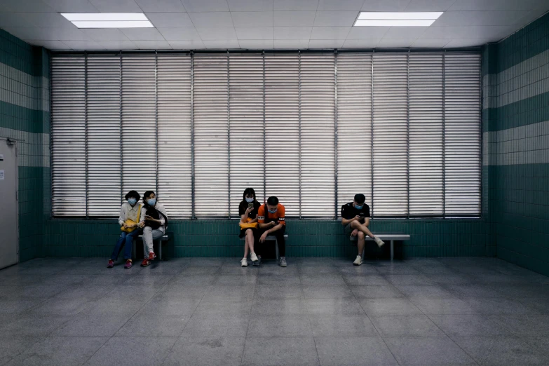 a group of people sitting next to each other in a room, by Fei Danxu, bus station, corona, waiting behind a wall, ap