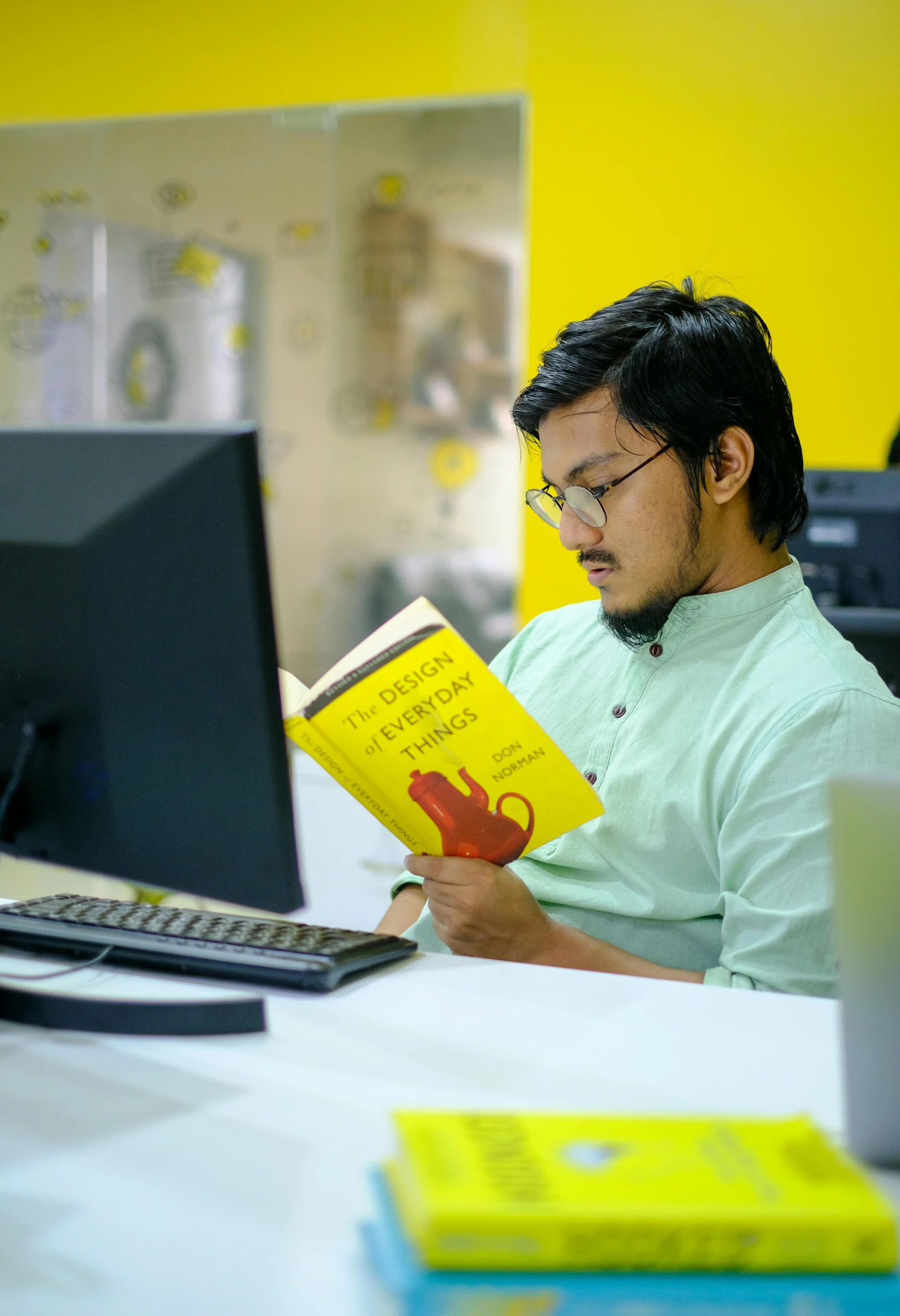 a man sitting at a desk reading a book, inspired by Bikash Bhattacharjee, pexels contest winner, wearing a modern yellow tshirt, programming, profile image, the librarian